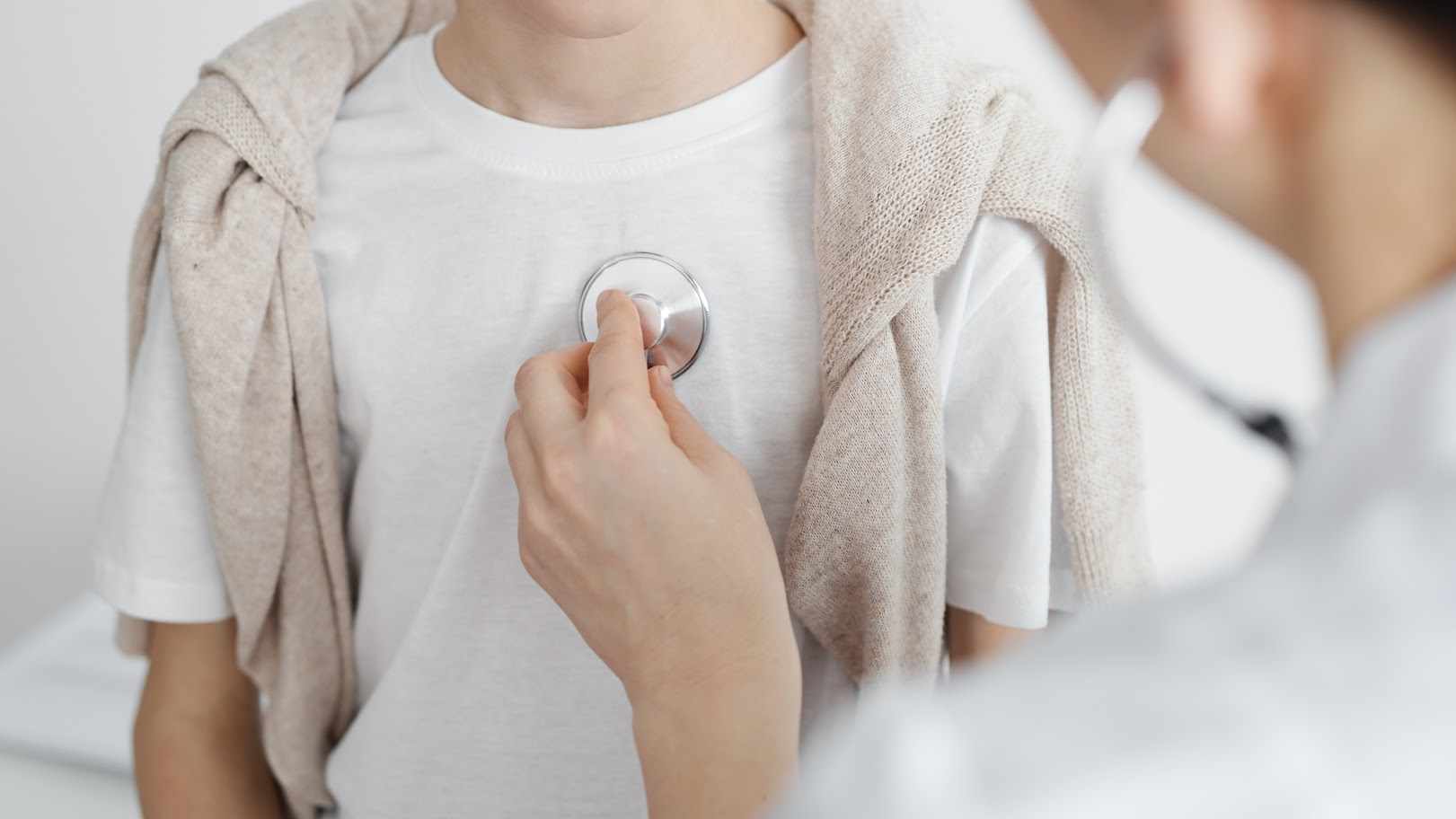  Lékař vyšetřuje pacienta přes tričko pomocí stetoskopu